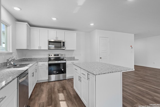 kitchen featuring appliances with stainless steel finishes, a kitchen island, a sink, and dark wood finished floors