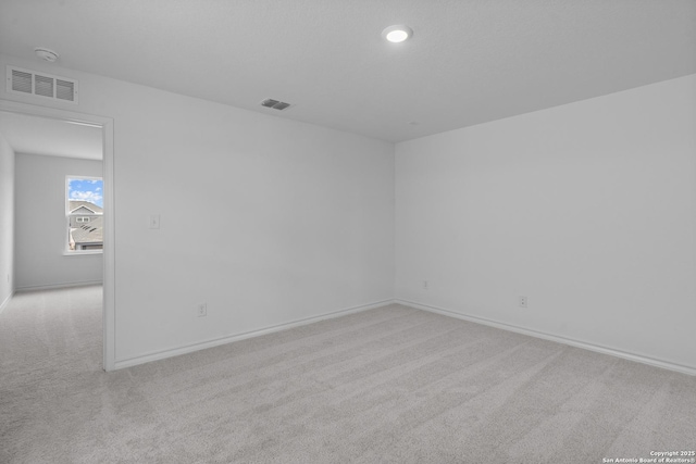 empty room with light colored carpet, visible vents, and baseboards