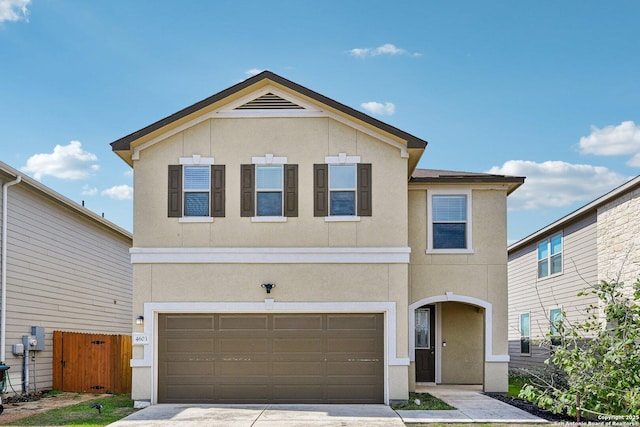 traditional-style home with driveway, an attached garage, fence, and stucco siding