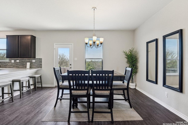 dining area featuring dark wood-style flooring, a notable chandelier, and baseboards