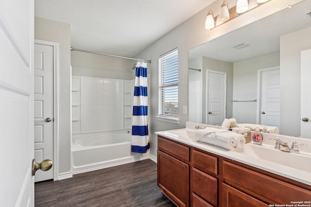 full bath featuring double vanity, shower / bath combination with curtain, visible vents, a sink, and wood finished floors