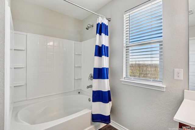 bathroom featuring a textured wall, shower / bath combo, and vanity