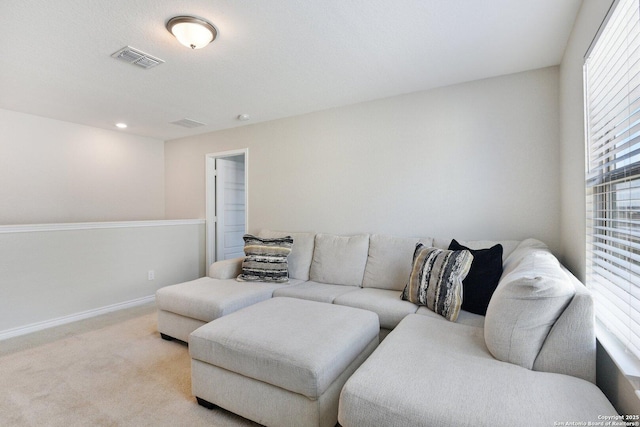 living area featuring light carpet, visible vents, and baseboards