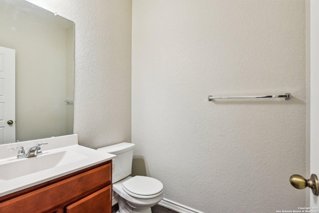 bathroom featuring a textured wall, vanity, and toilet