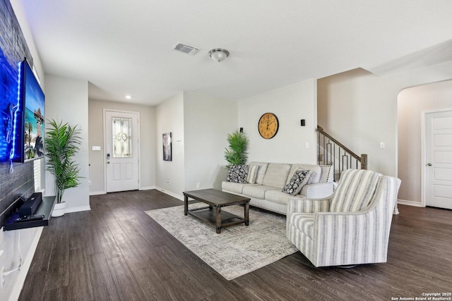 living area featuring baseboards, visible vents, arched walkways, stairway, and wood finished floors