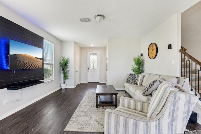 living room with stairs, visible vents, baseboards, and wood finished floors