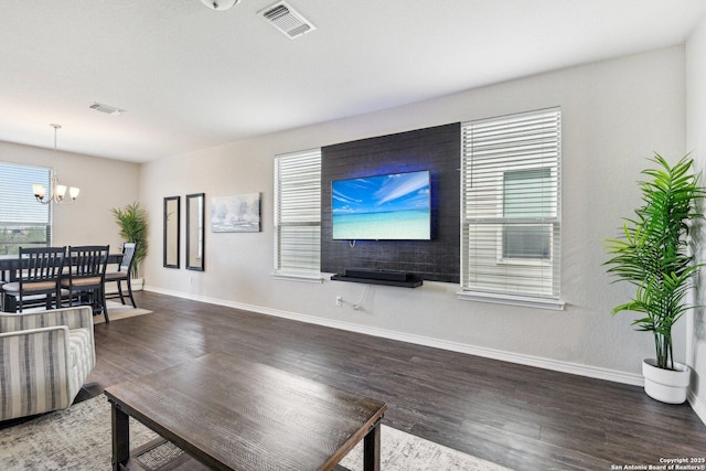 living area featuring baseboards, wood finished floors, visible vents, and an inviting chandelier