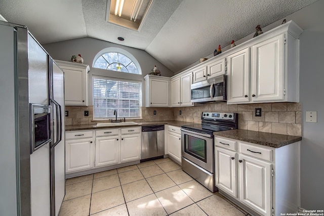 kitchen featuring dark countertops, white cabinets, stainless steel appliances, and a sink