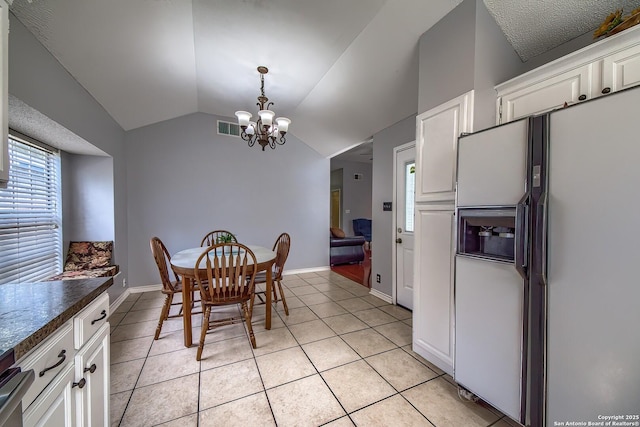 dining space with lofted ceiling, light tile patterned flooring, visible vents, and an inviting chandelier