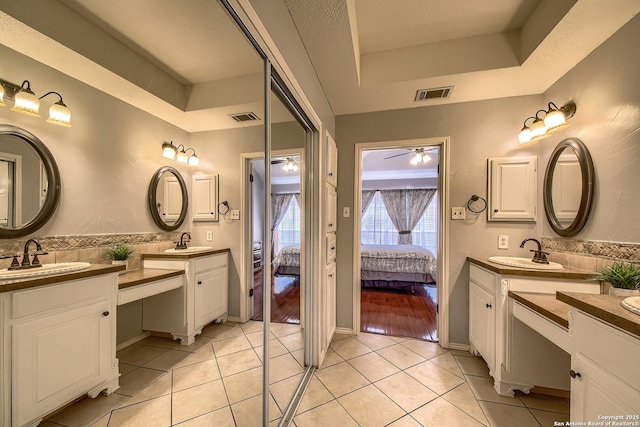 bathroom with a raised ceiling, visible vents, and a sink