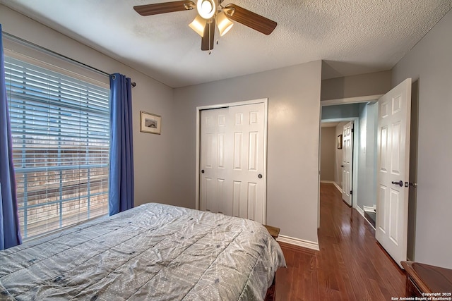 bedroom with a closet, ceiling fan, a textured ceiling, wood finished floors, and baseboards