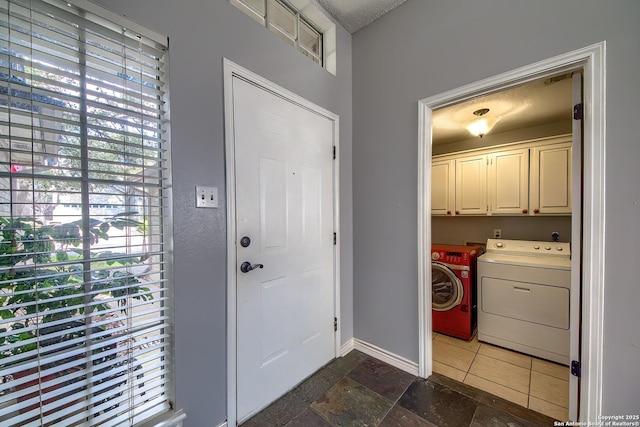 laundry area featuring stone tile flooring, cabinet space, hookup for an electric dryer, and baseboards