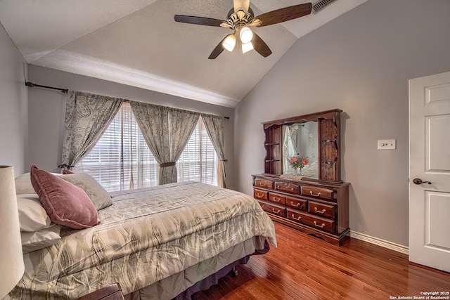 bedroom with ceiling fan, wood finished floors, visible vents, baseboards, and vaulted ceiling