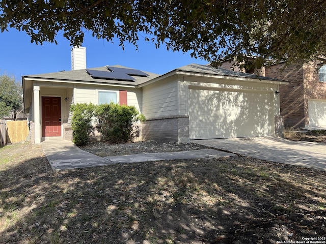 view of front of home featuring brick siding, a chimney, solar panels, concrete driveway, and a garage