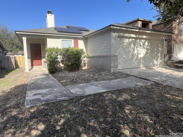 view of front of property featuring a garage, concrete driveway, solar panels, fence, and brick siding