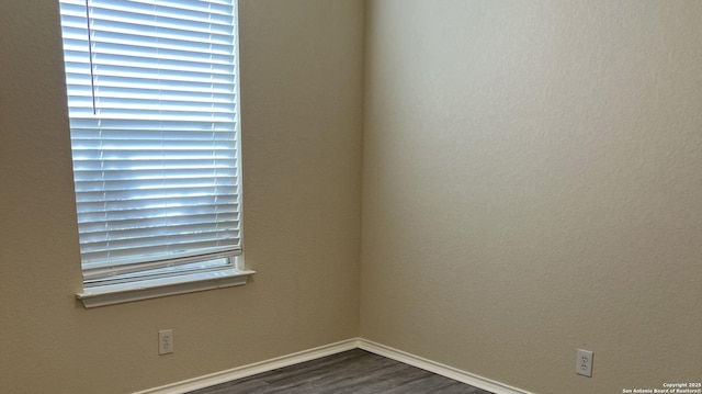 empty room featuring baseboards and dark wood-style flooring