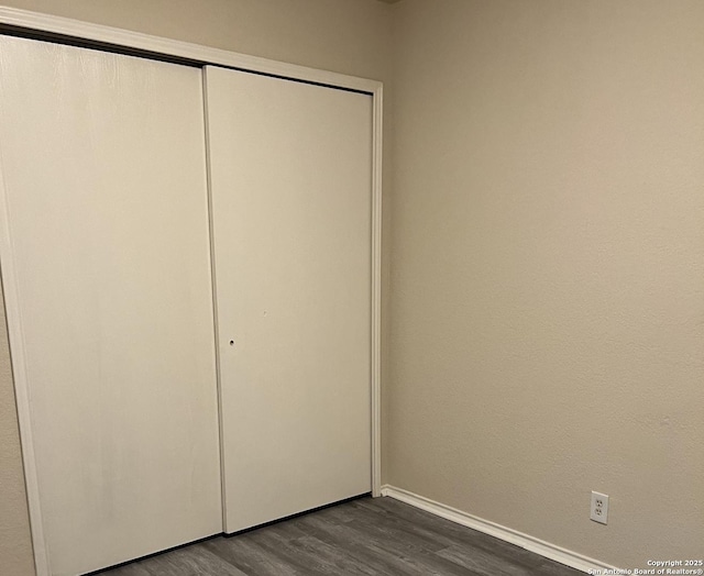 unfurnished bedroom featuring dark wood-style floors and a closet