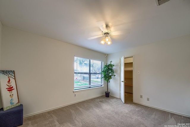 carpeted spare room featuring visible vents and a ceiling fan