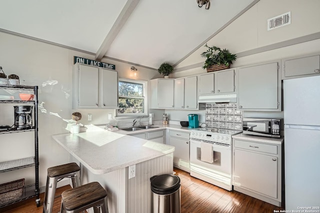 kitchen with white appliances, visible vents, a peninsula, under cabinet range hood, and a sink