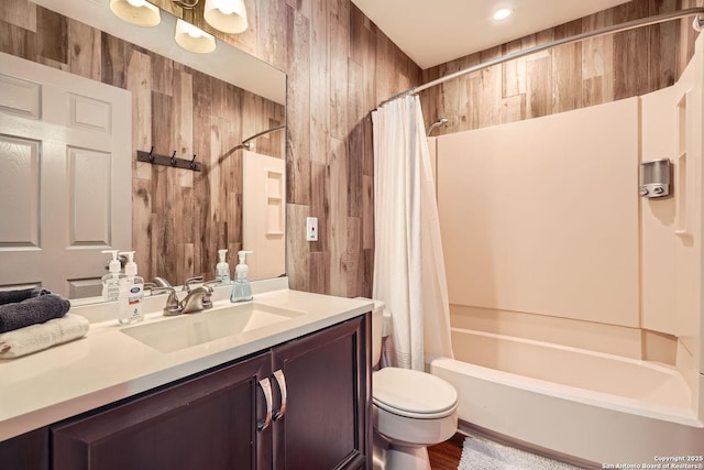 bathroom with shower / bath combo, wood walls, vanity, and toilet