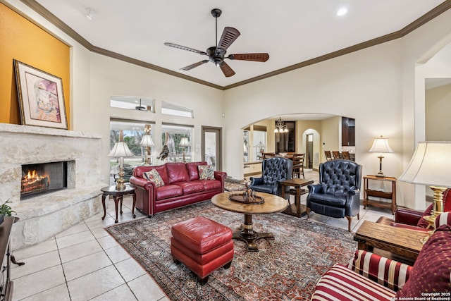 living room with ornamental molding, arched walkways, a fireplace, and tile patterned floors