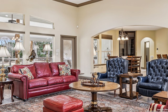 living area with a chandelier, arched walkways, and a towering ceiling