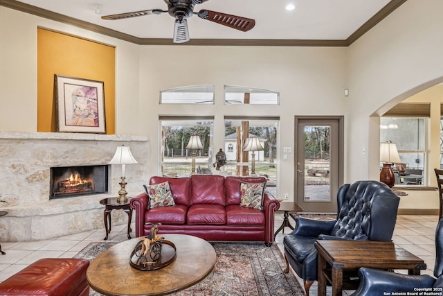 tiled living area with arched walkways, a fireplace, a wealth of natural light, and crown molding