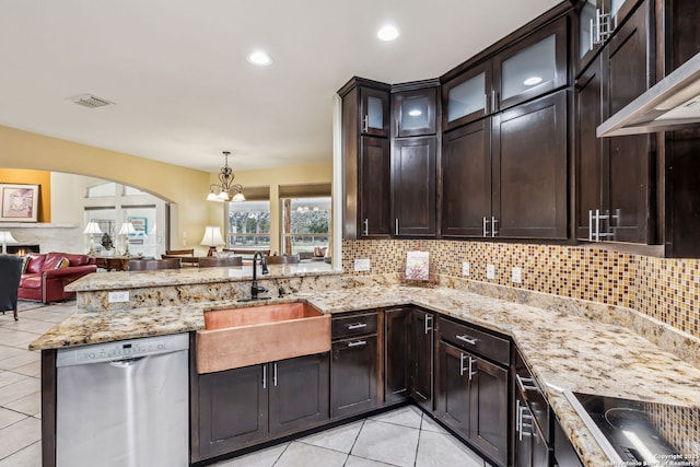 kitchen with dark brown cabinetry, a peninsula, a sink, stainless steel dishwasher, and wall chimney exhaust hood