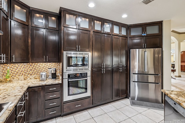 kitchen with light tile patterned floors, tasteful backsplash, light stone counters, and stainless steel appliances