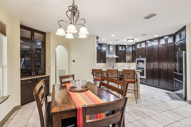 dining room with light tile patterned floors, arched walkways, visible vents, and an inviting chandelier