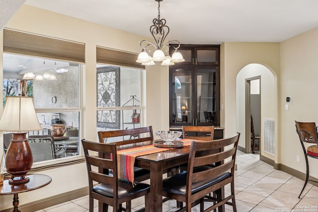 dining space featuring arched walkways, light tile patterned floors, visible vents, an inviting chandelier, and baseboards