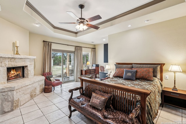 bedroom with access to exterior, crown molding, a raised ceiling, a stone fireplace, and tile patterned floors