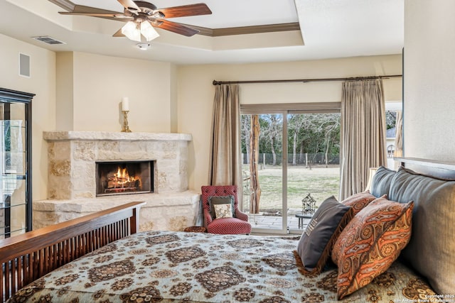 bedroom with a fireplace, visible vents, a ceiling fan, access to outside, and a tray ceiling