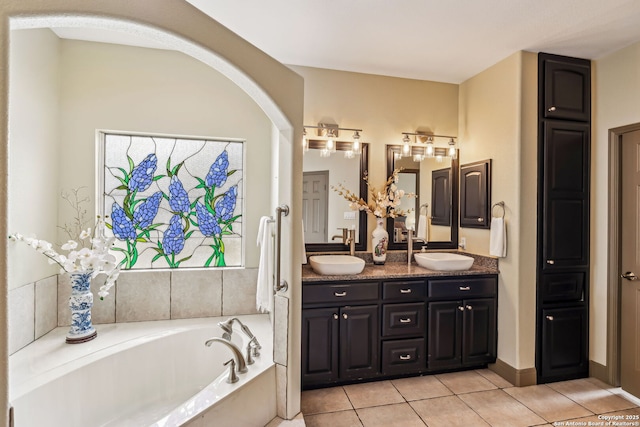 bathroom with double vanity, a garden tub, a sink, and tile patterned floors