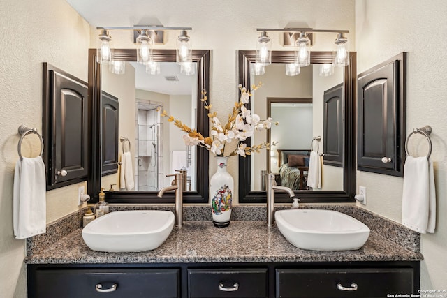 bathroom with double vanity, a sink, and a textured wall