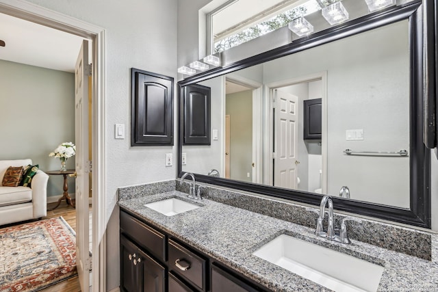 full bathroom with double vanity, a sink, and wood finished floors