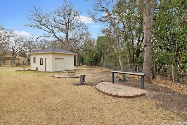 view of yard with an outdoor fire pit, fence, and an outbuilding