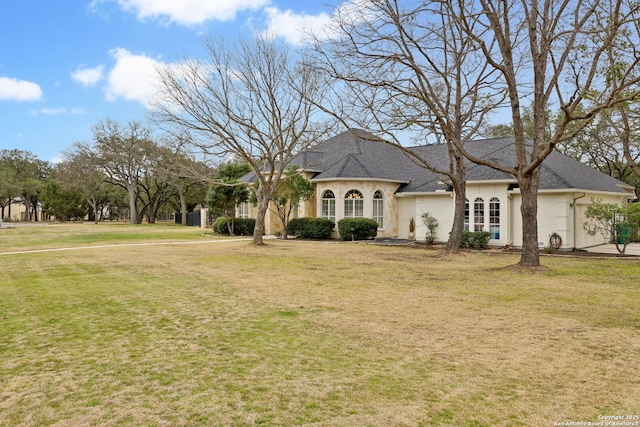 french country home featuring roof with shingles, a front yard, and stucco siding