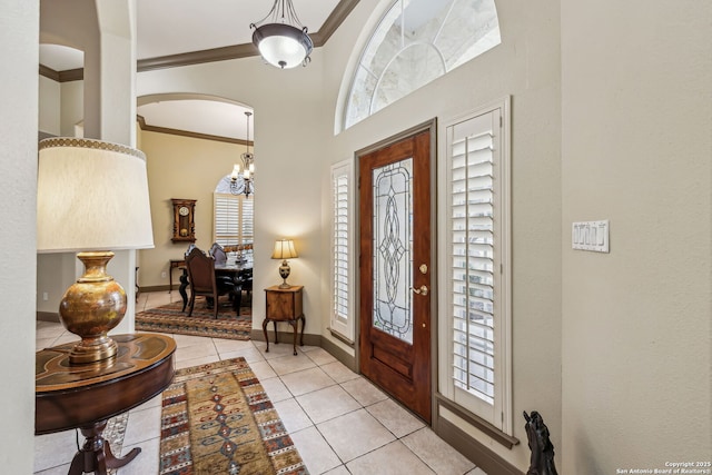 tiled entryway with baseboards and crown molding