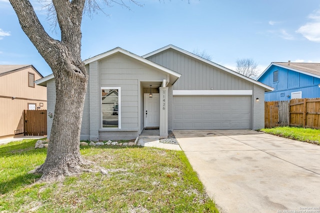 view of front of property with an attached garage, fence, concrete driveway, and brick siding