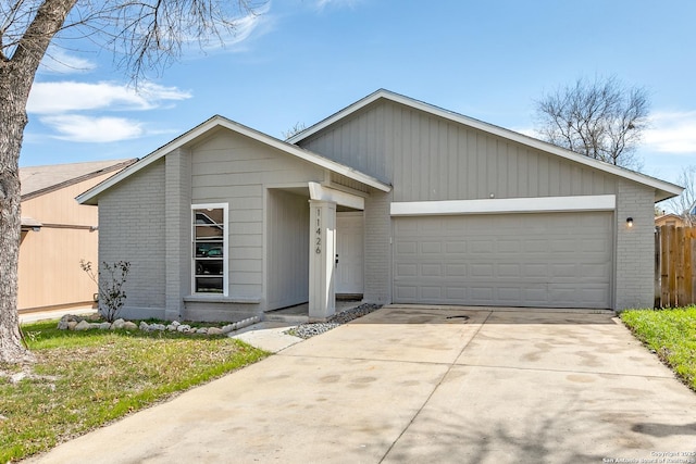 mid-century modern home featuring an attached garage, fence, concrete driveway, and brick siding