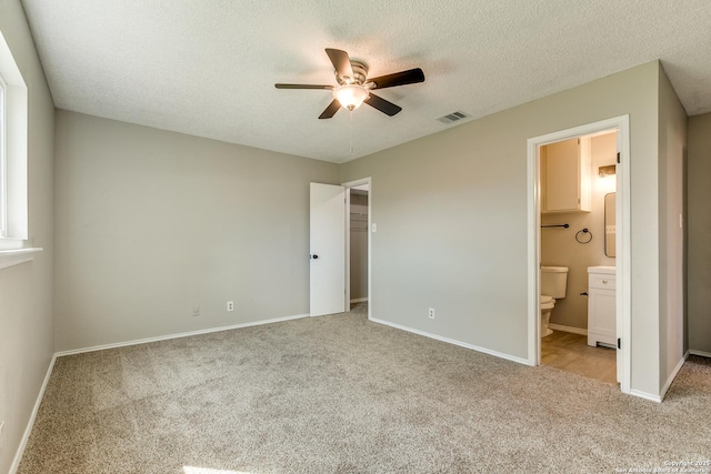 unfurnished bedroom featuring a textured ceiling, carpet, visible vents, and baseboards