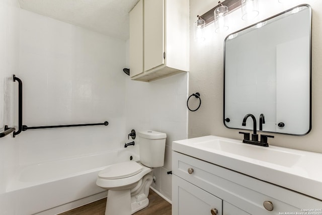 bathroom with toilet, wood finished floors,  shower combination, a textured ceiling, and vanity