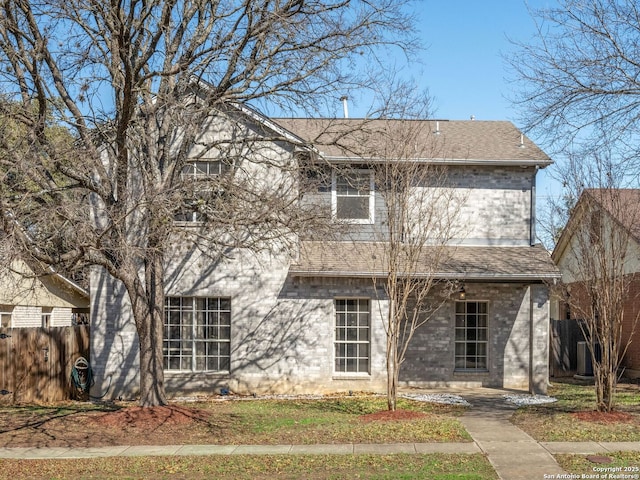 view of front of home with a shingled roof, fence, and brick siding