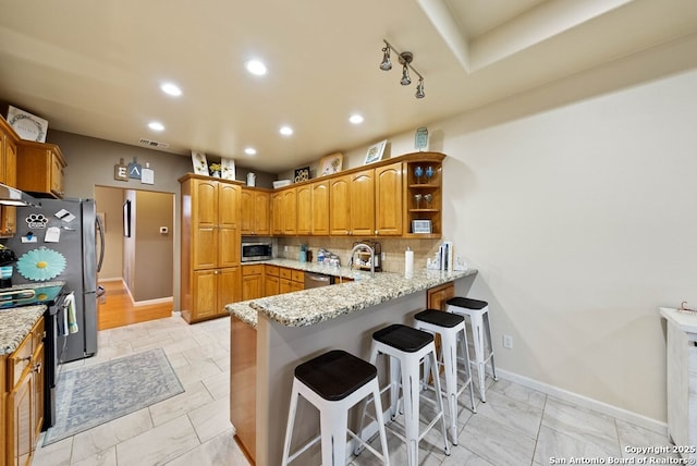 kitchen featuring visible vents, brown cabinets, a peninsula, light stone countertops, and stainless steel appliances