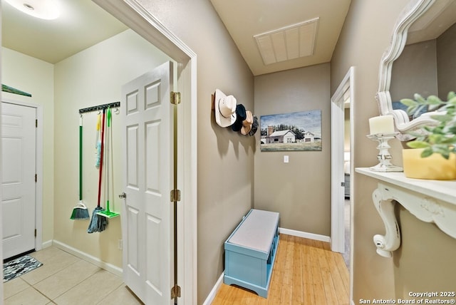 hallway with light wood finished floors, baseboards, and visible vents