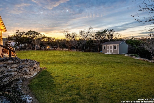 yard at dusk featuring an outbuilding and a storage unit