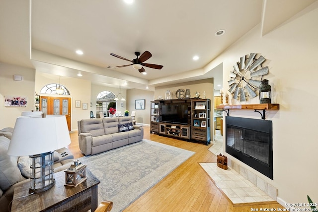 living area with baseboards, a tiled fireplace, ceiling fan, light wood-style floors, and recessed lighting