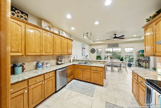 kitchen featuring tasteful backsplash, appliances with stainless steel finishes, a peninsula, a tray ceiling, and a sink