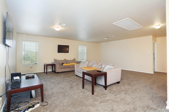 carpeted living room featuring attic access, visible vents, and baseboards